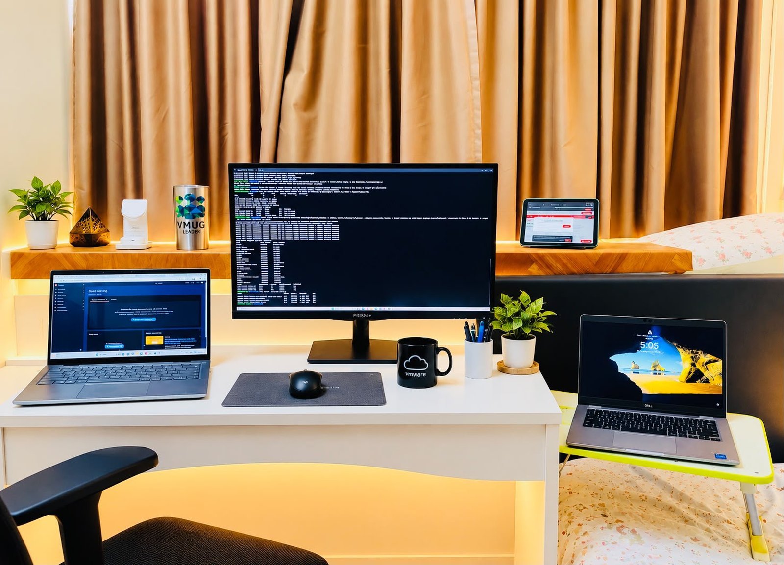 The home lab desk: the lab laptop under an external monitor showing a terminal, an iPad on the shelf showing the app, and an office laptop on the right